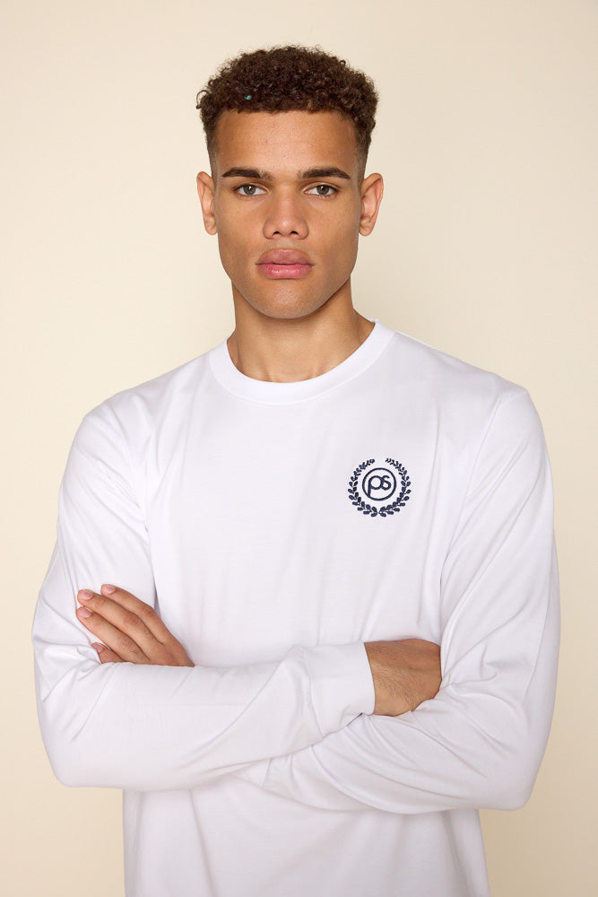 Cropped photo of male model wearing a white long sleeve shirt with a monogram PS surrounded by victory wreath