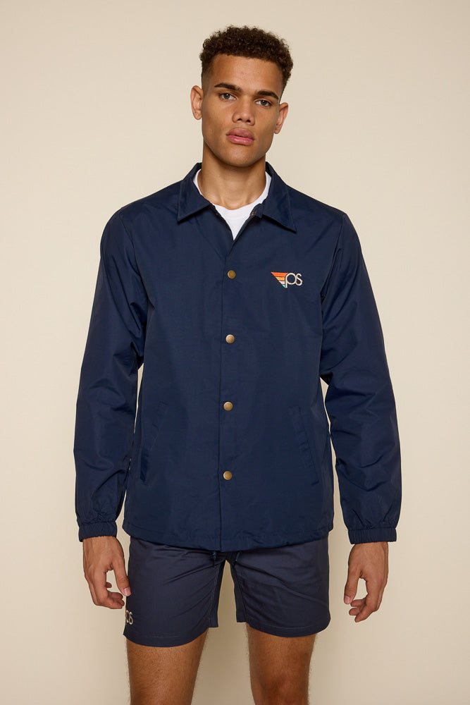 Frontal view of male model wearing navy water resistant jacket with "PS" graphic on the top upper left chest