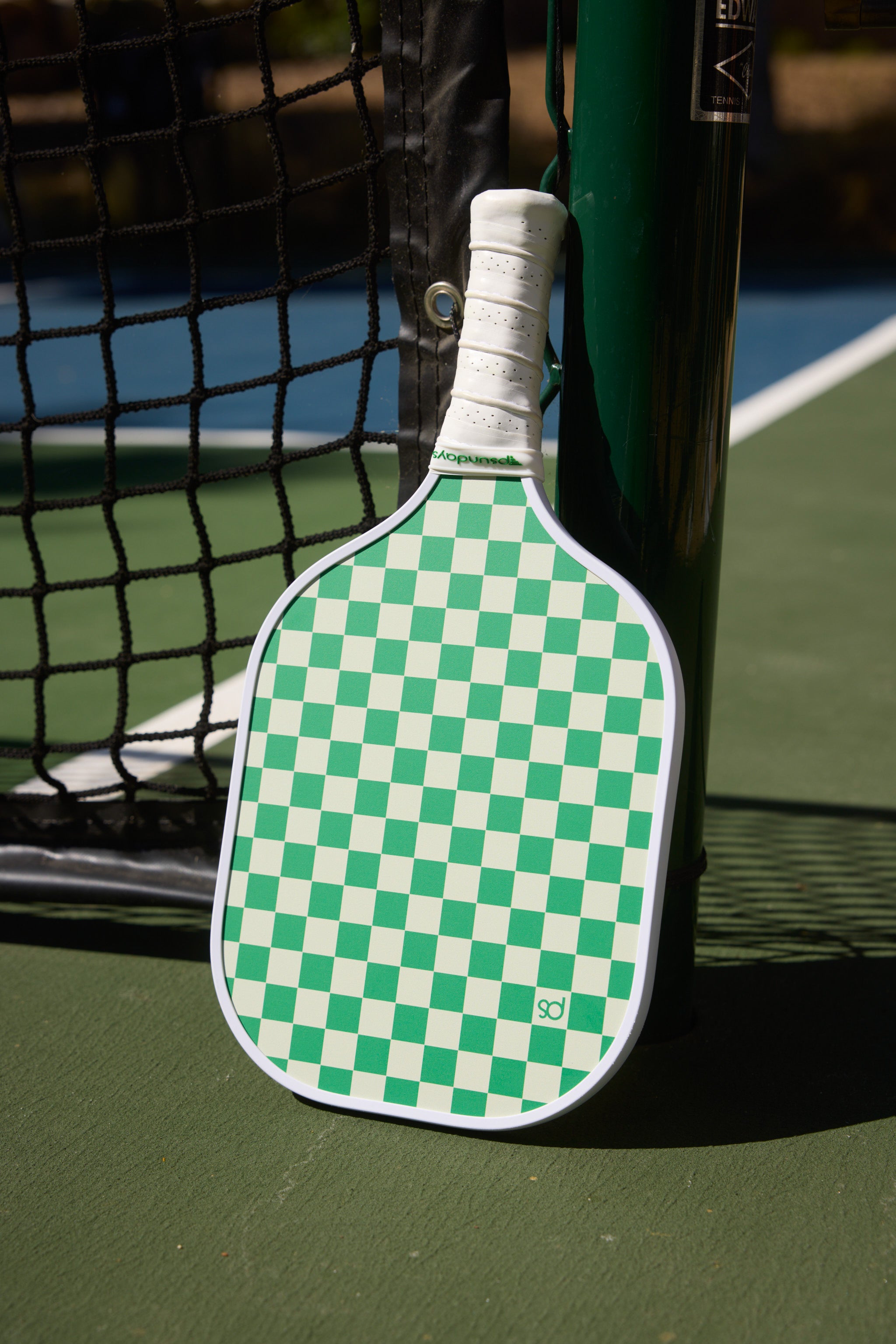 Green and beige pickleball paddle with a small PS on one beige squared.  Handle is white ribbed grip