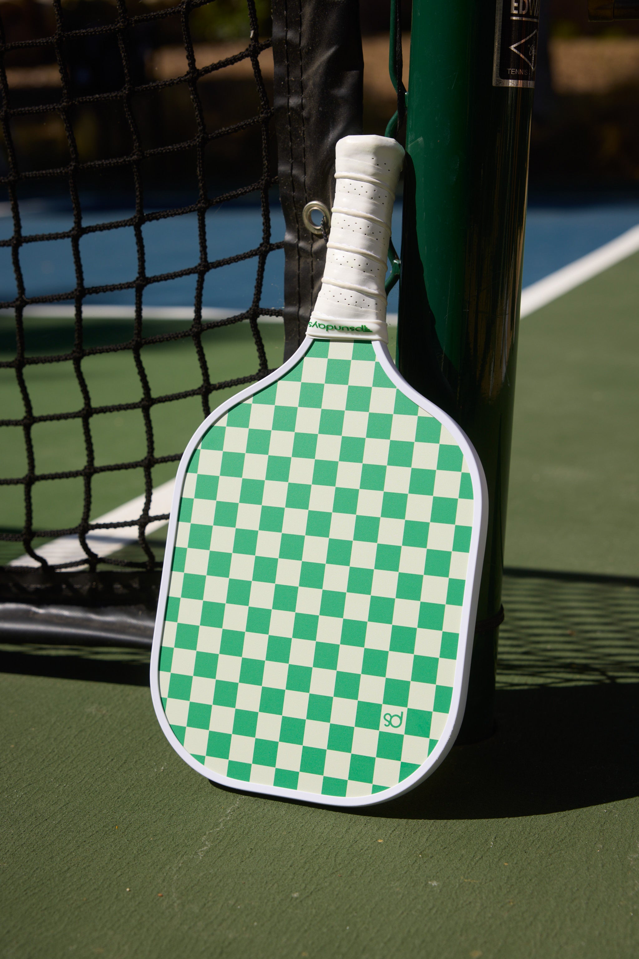 Green and beige pickleball paddle with a small PS on one beige squared. Handle is white ribbed grip