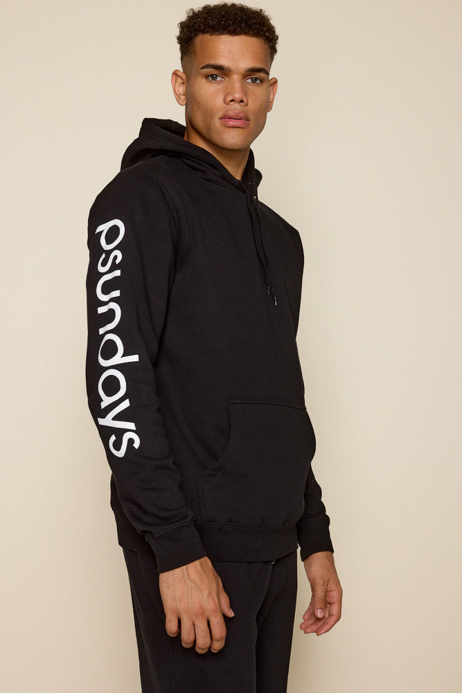Close up picture of a male model wearing a black hoodie with Psundays logo in white print on right sleeve